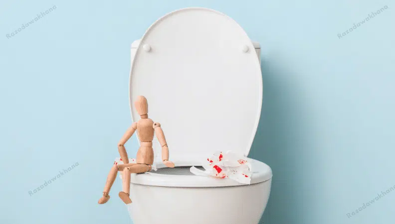 Wooden figure sits on a toilet with tissues stained red nearby, against a blue background.