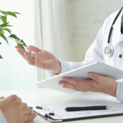 A doctor with a tablet discussing with a patient whose hands are on a clipboard.