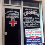 Glass door with text and red cross, indicating a medical facility's entrance.