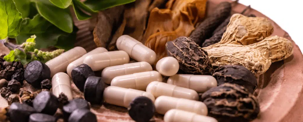 Herbal supplements and capsules displayed with various natural herbs and dried roots, symbolizing alternative medicine and natural health remedies